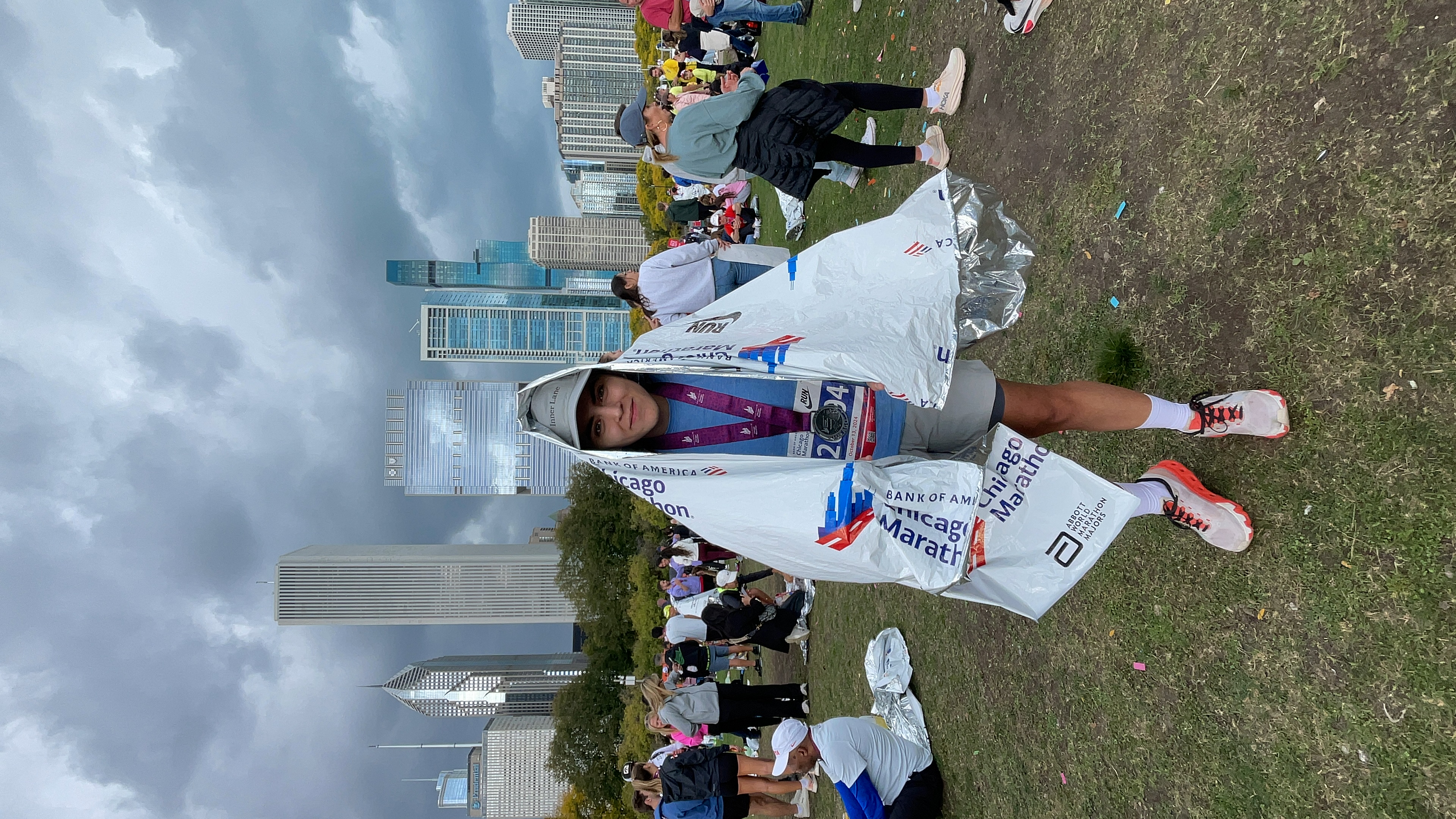 A young woman stands in a field post-marathon surrounded by other runners