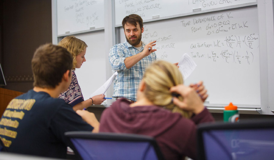Faculty discussing class materials in front of a white board.