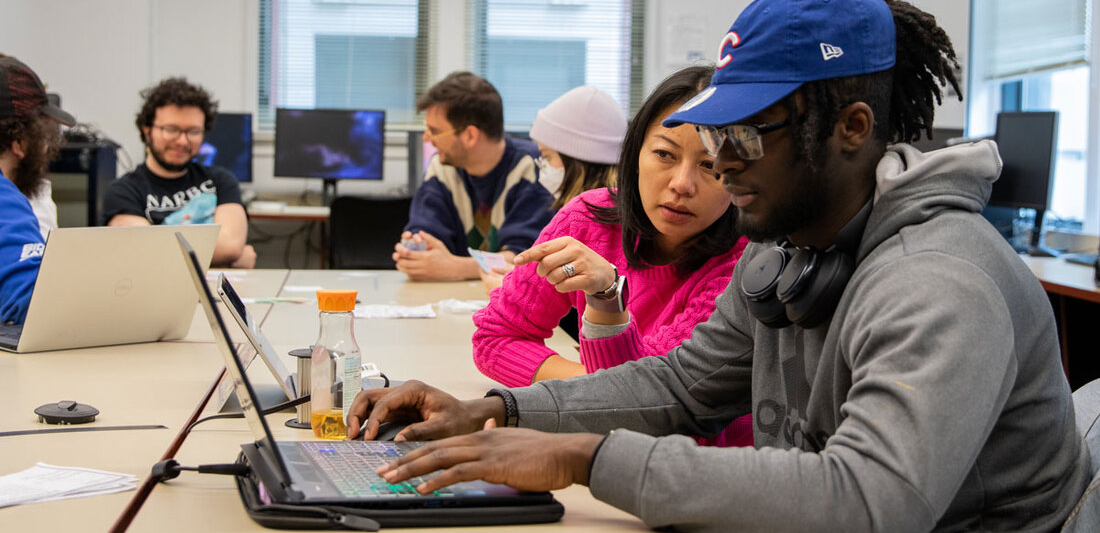 faculty member and student discuss work on laptop