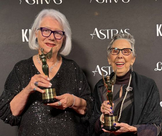 Catherine Marienau and Gail Zelitzky stand side by side holding awards for their podcast Women Over 70-Aging Reimagined