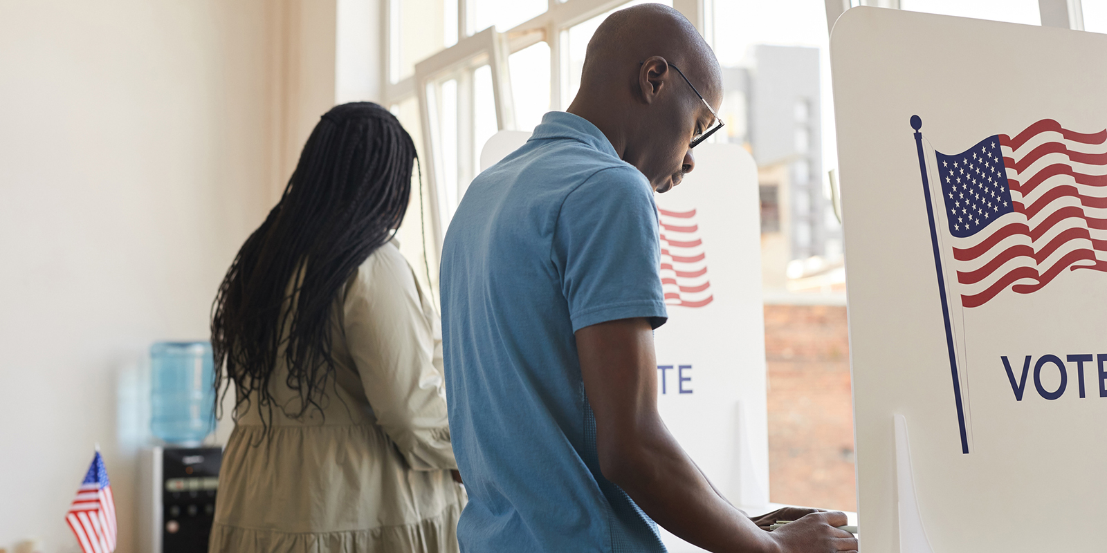Two people stand at voting booths