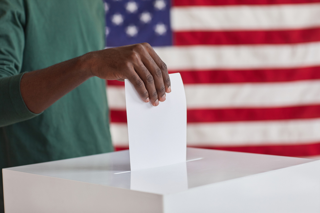 A person putting a ballot into a voting box.