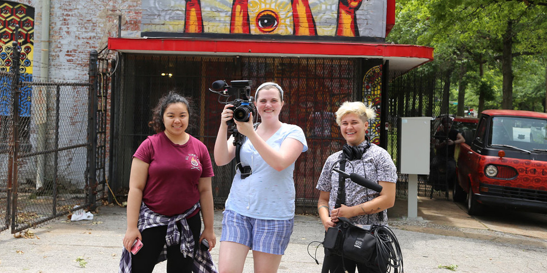 Three filmmakers smiling with their equipment