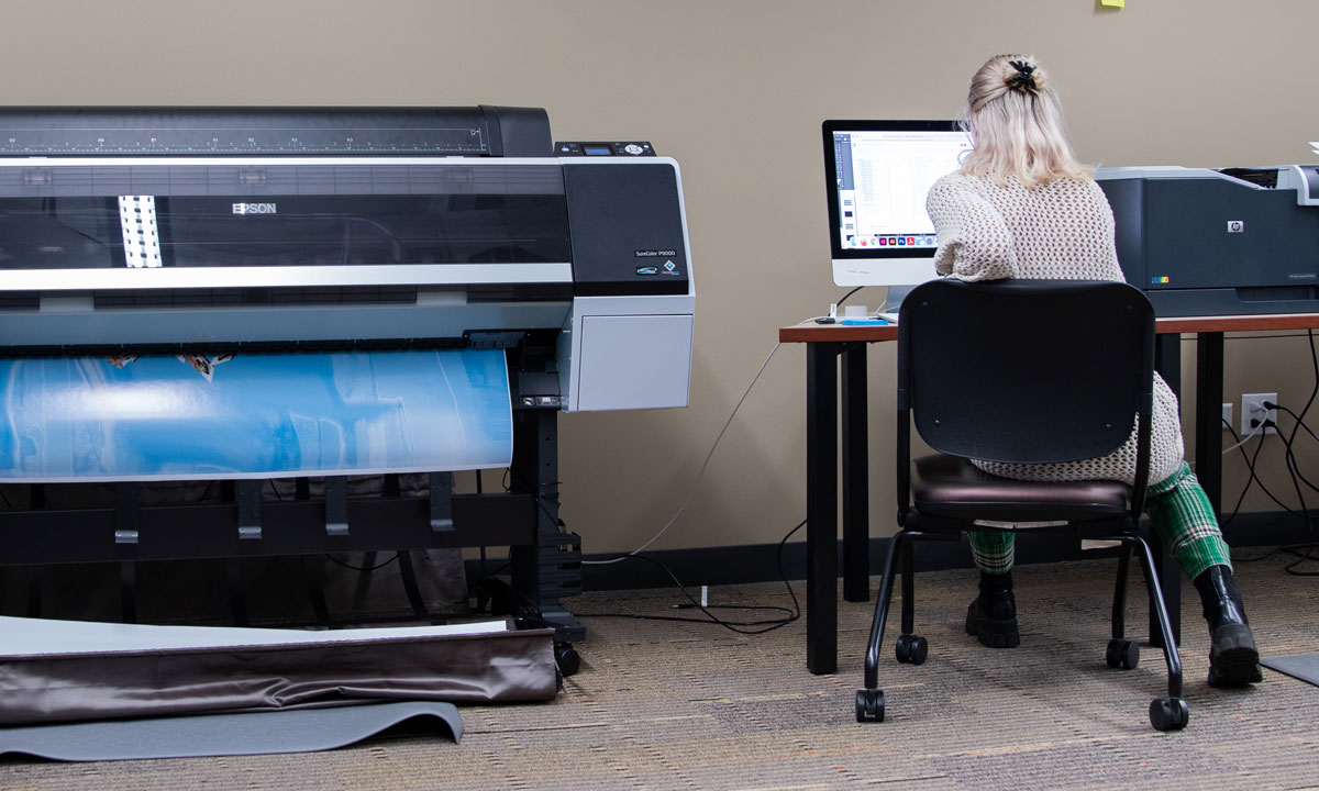 student working with a large printer