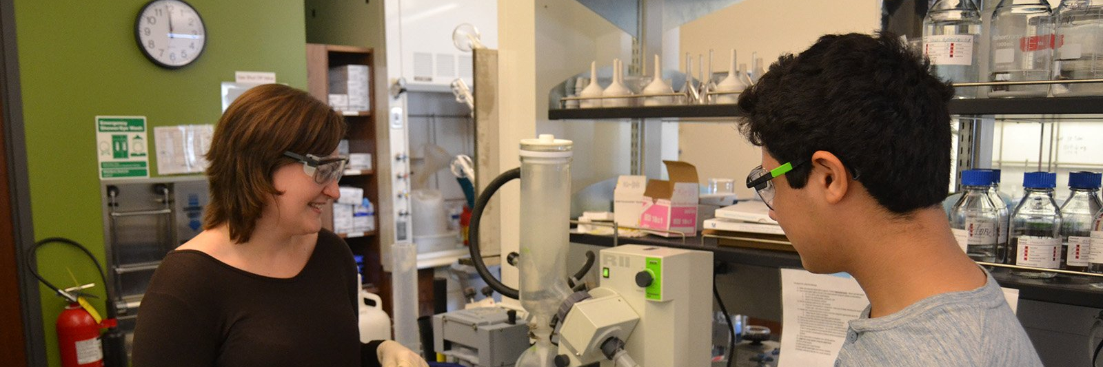 Two students laughing while observing samples in a lab.
