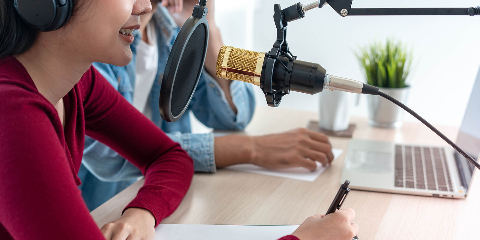 woman was speaking on a morning radio station broadcasting a news program and men preparing the content via computers.