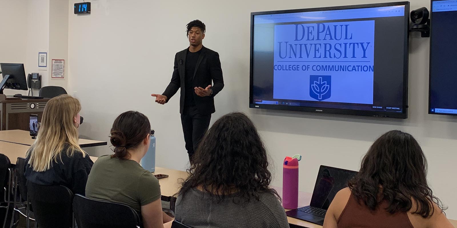 Nate Mitchell, a former contestant on The Bachelor, stands in front of a classroom of students