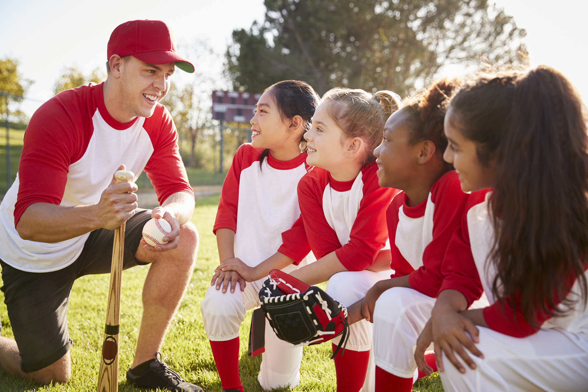 Coach and girls on baseball team meeting
