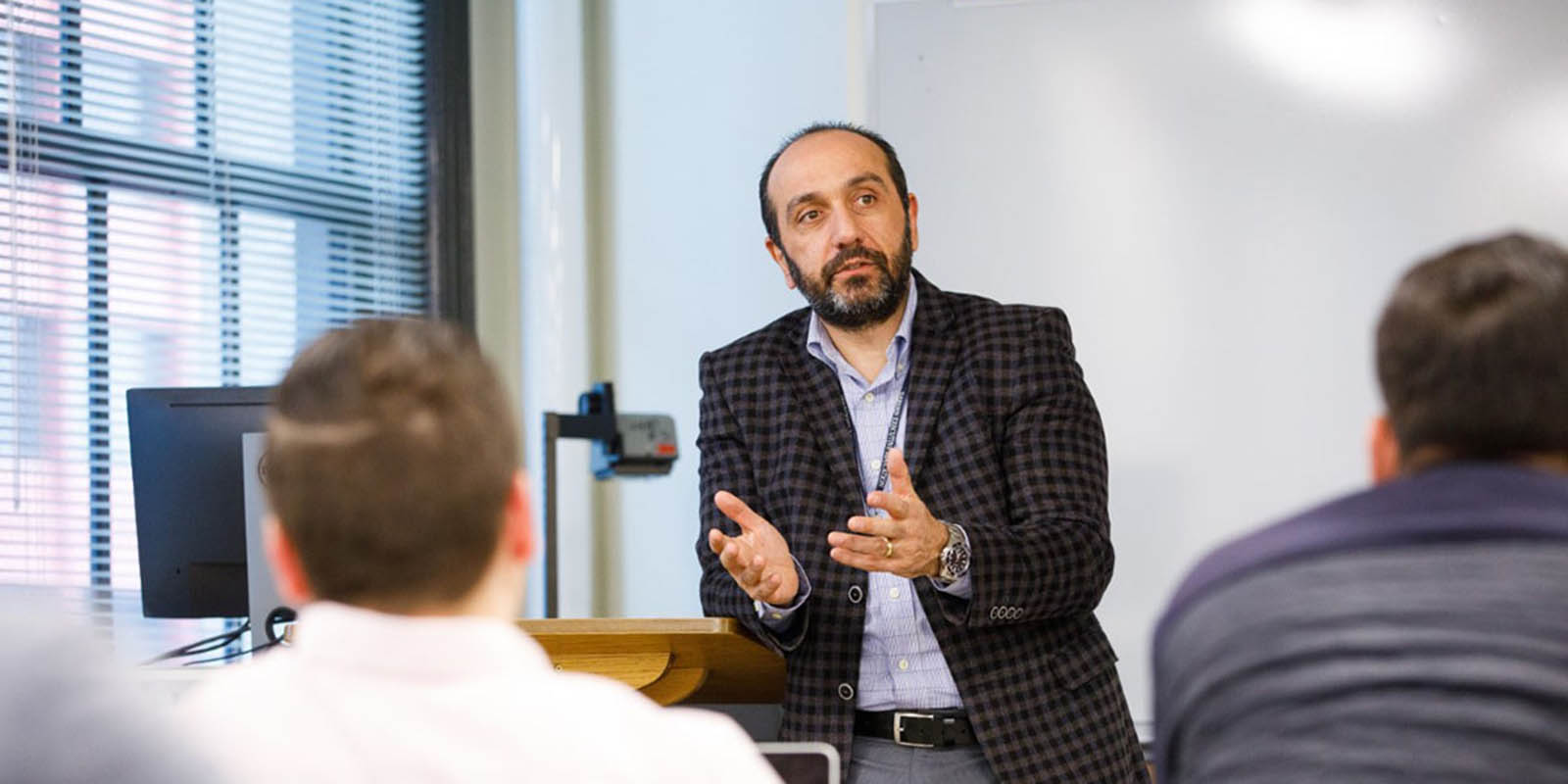 Nezih Altay leans on podium in a classroom giving a lecture