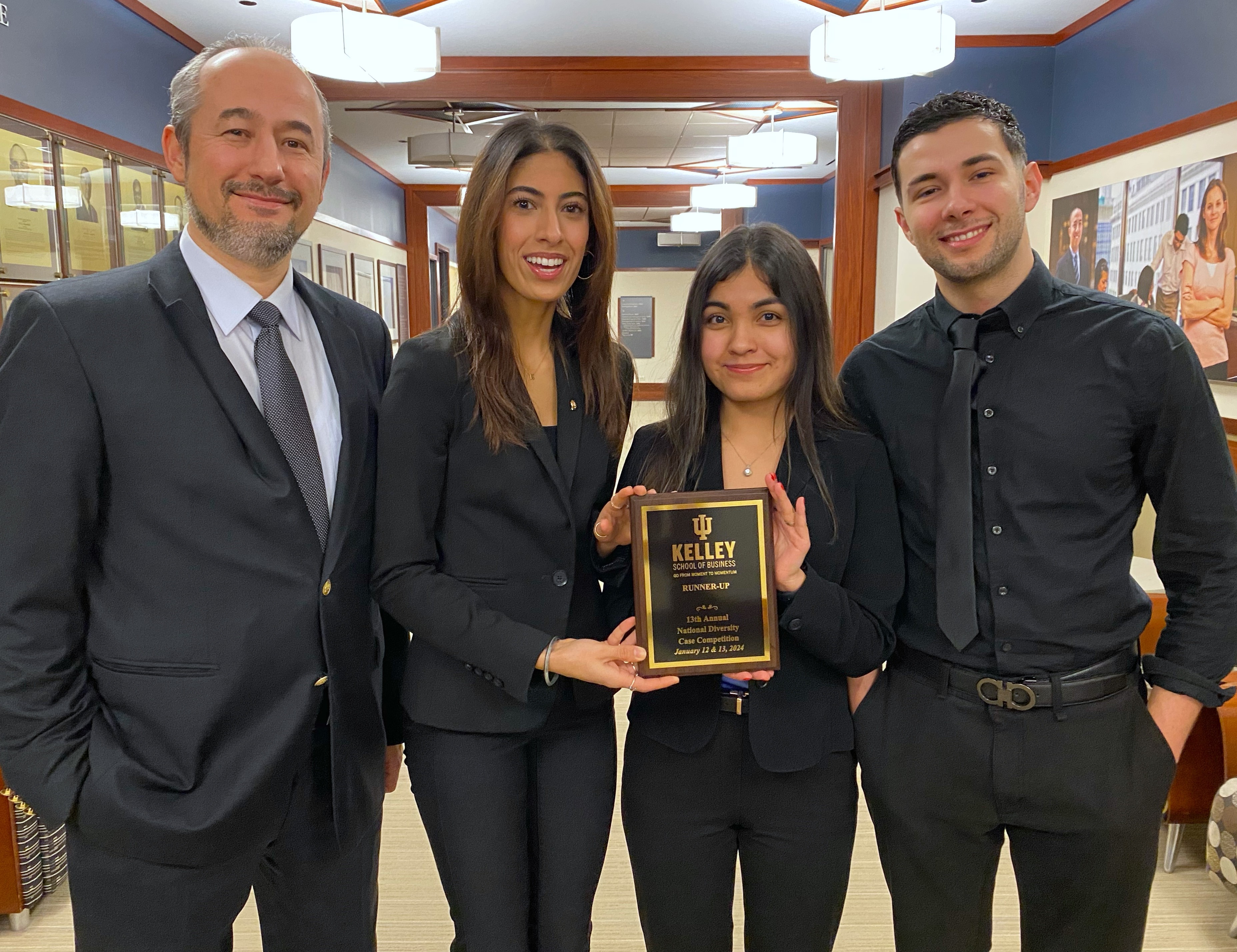 A group of students and a professor pose with a plaque