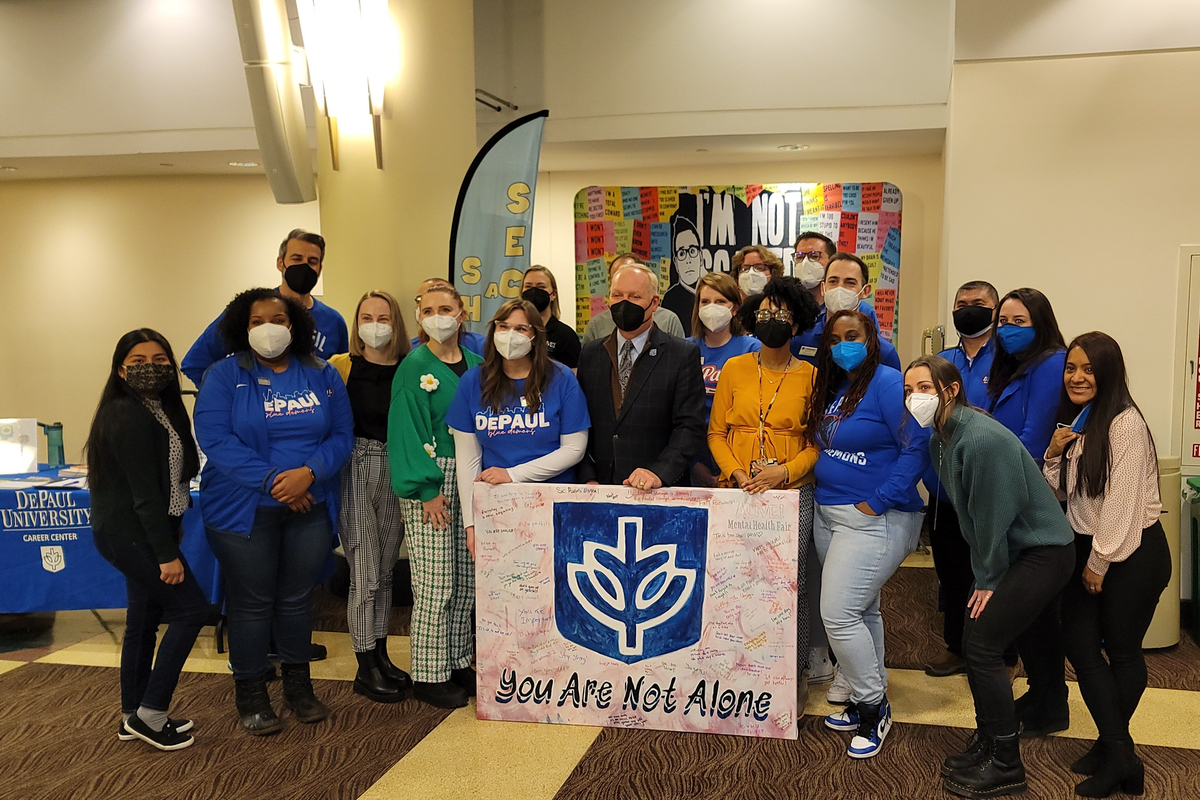 Students, staff and faculty gather around a poster stating