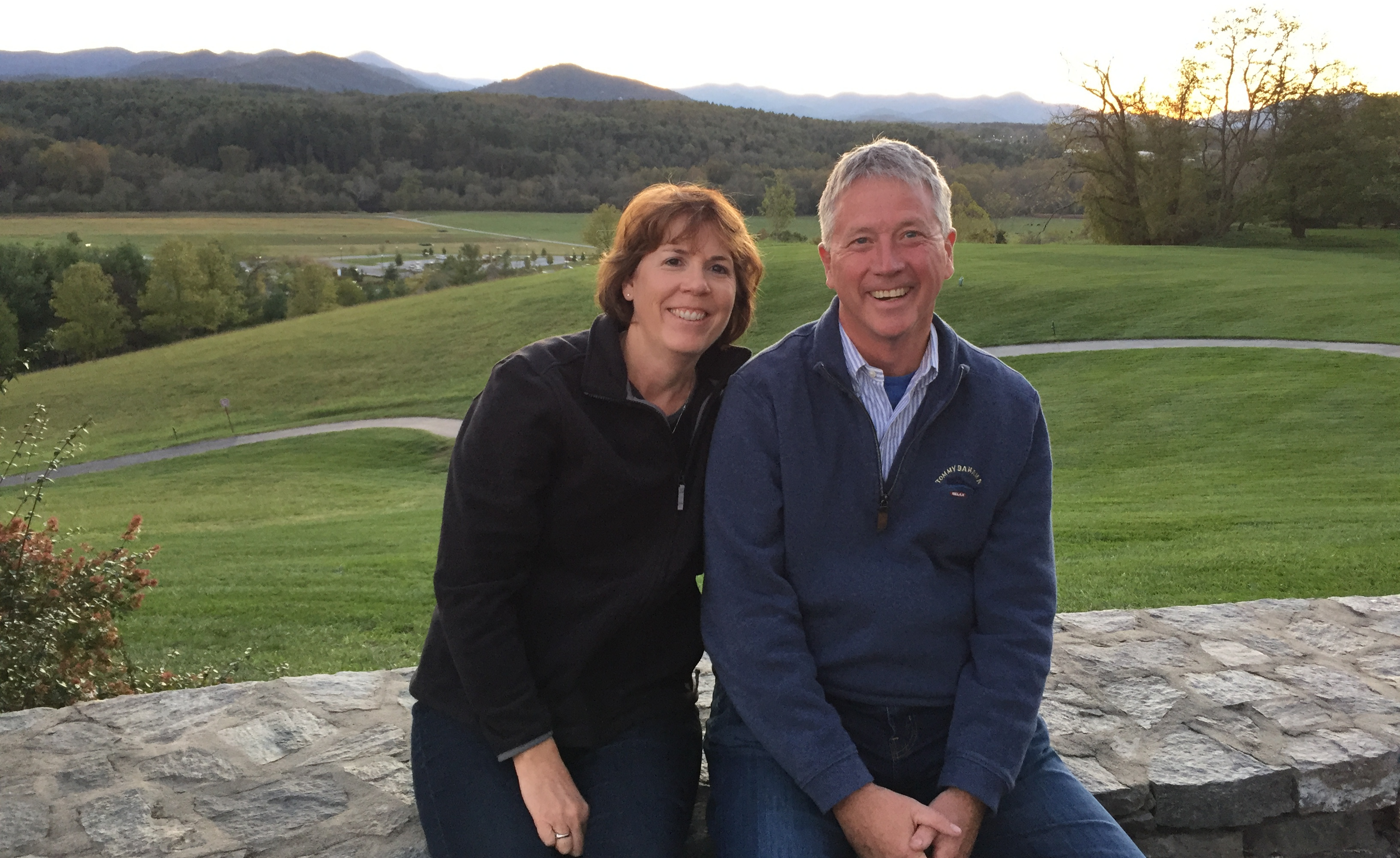 A man and woman posed in front of a hillside