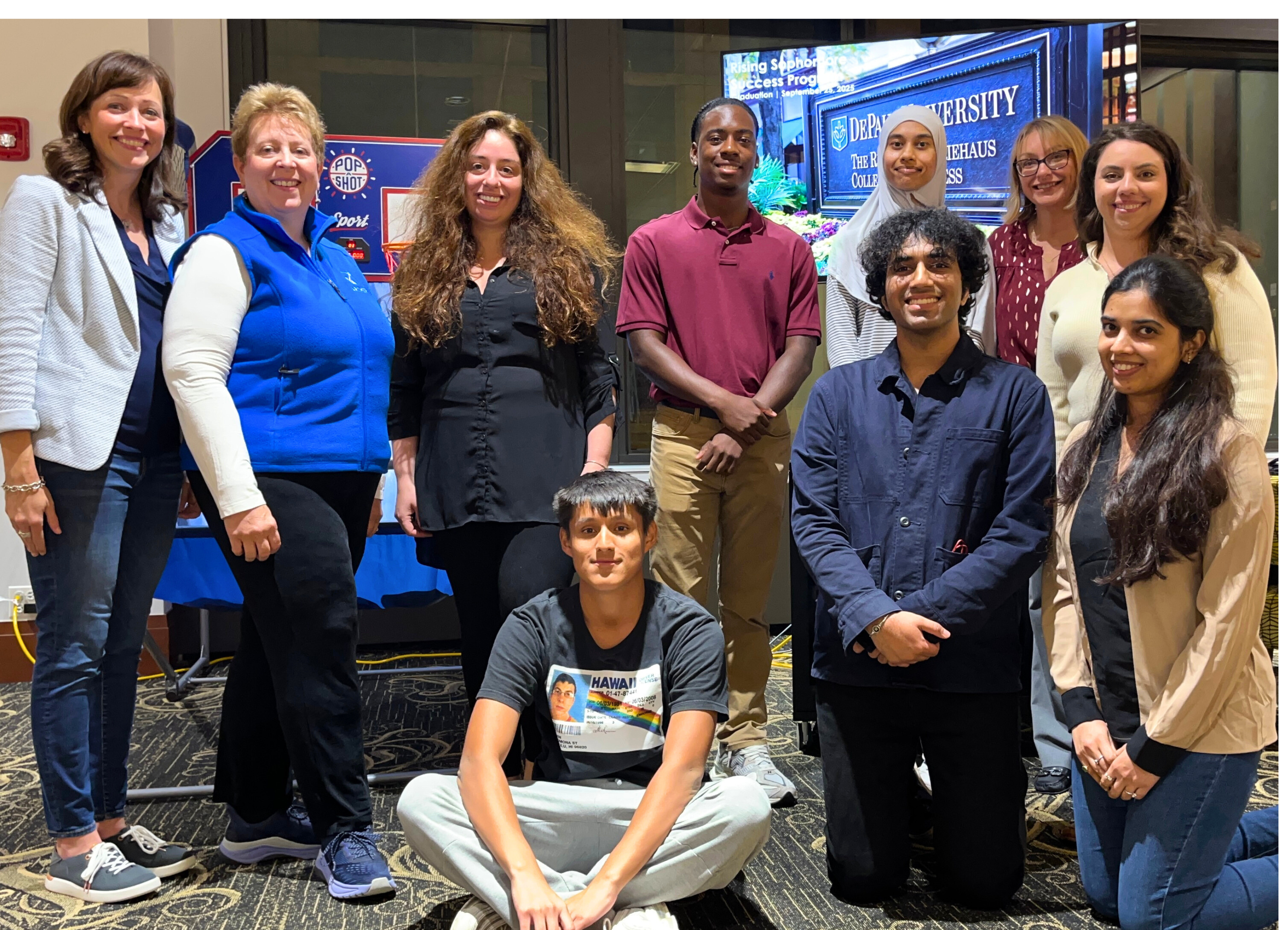 A group of professionals and students in casual clothing pose indoors