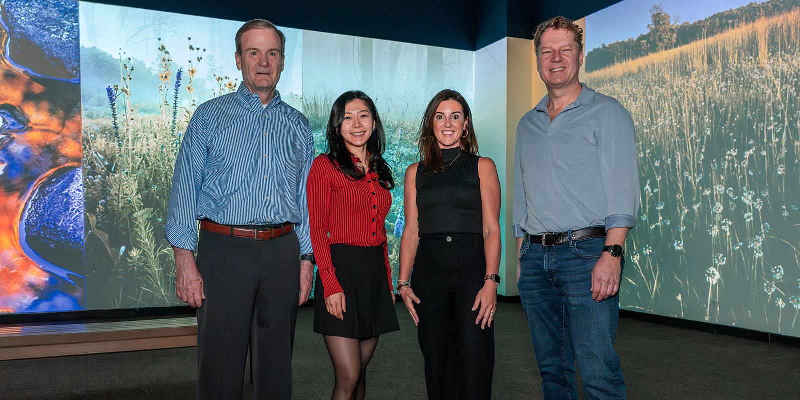 Yaxi Yang stands in front of a digital display of nature photos at the nature museum