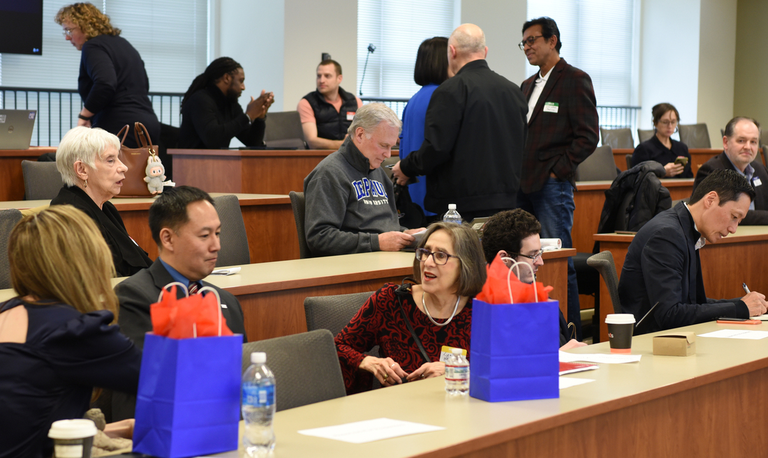 A lecture hall with a mix of young and middle aged professionals engaged in networking.