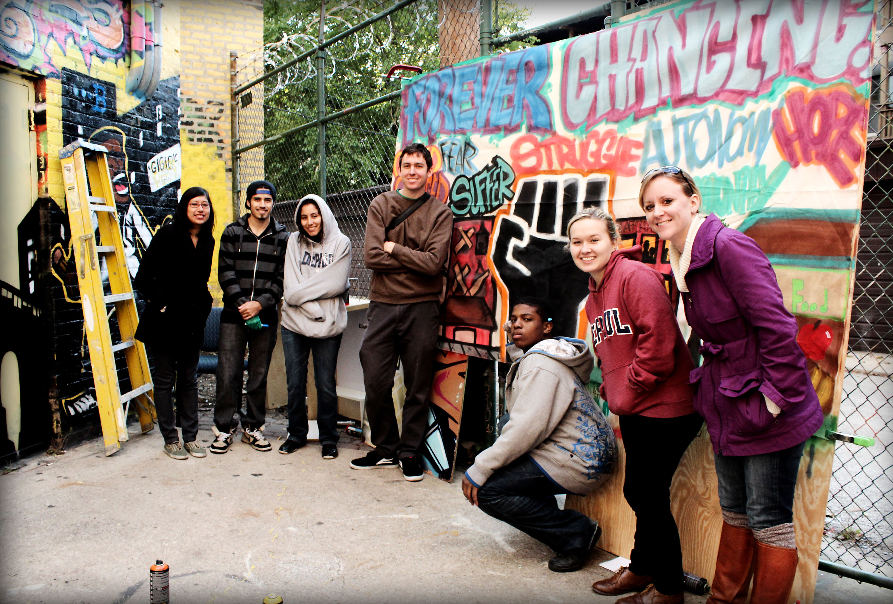 DePaul students stand together in front of a chain-link fence