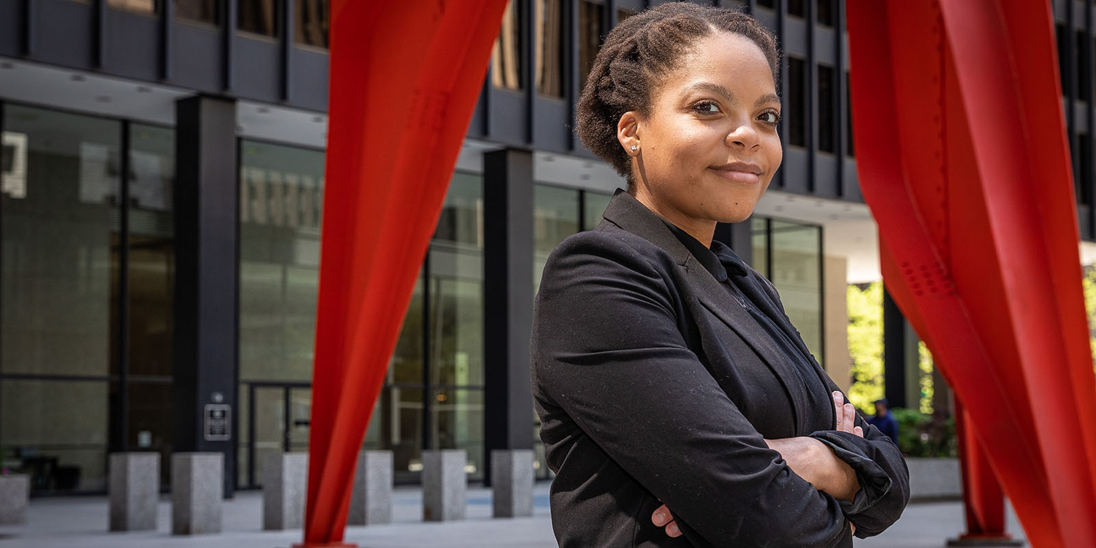 SaDella Duval d'Adrian stands with arms folded in a courtyard.