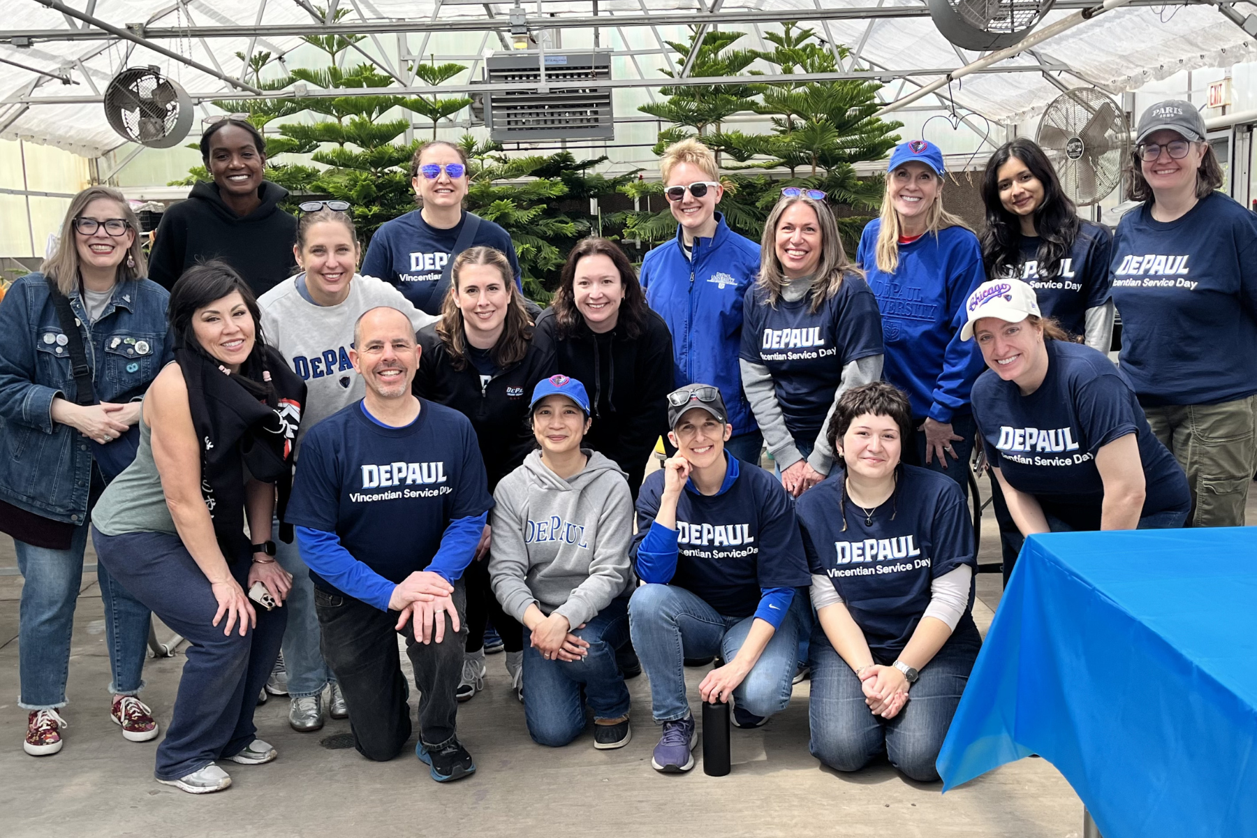 Fifteen people kneel and stand in a group with matching DePaul shirts.