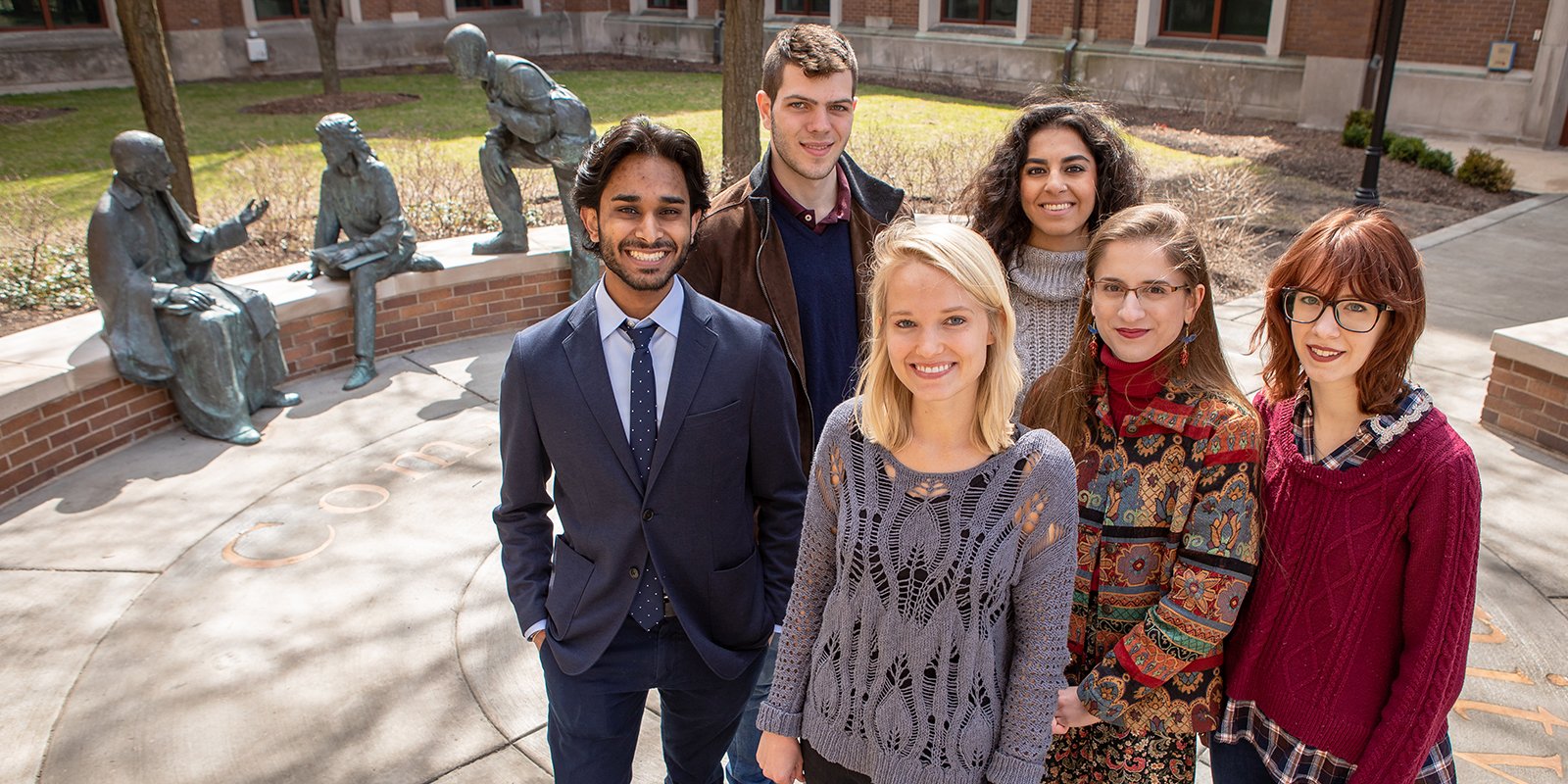 A group of students standing in front of the Saint Vincent DePaul statue