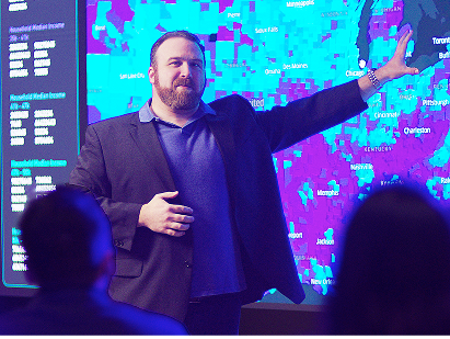 faculty member pointing to data visualization on large screen