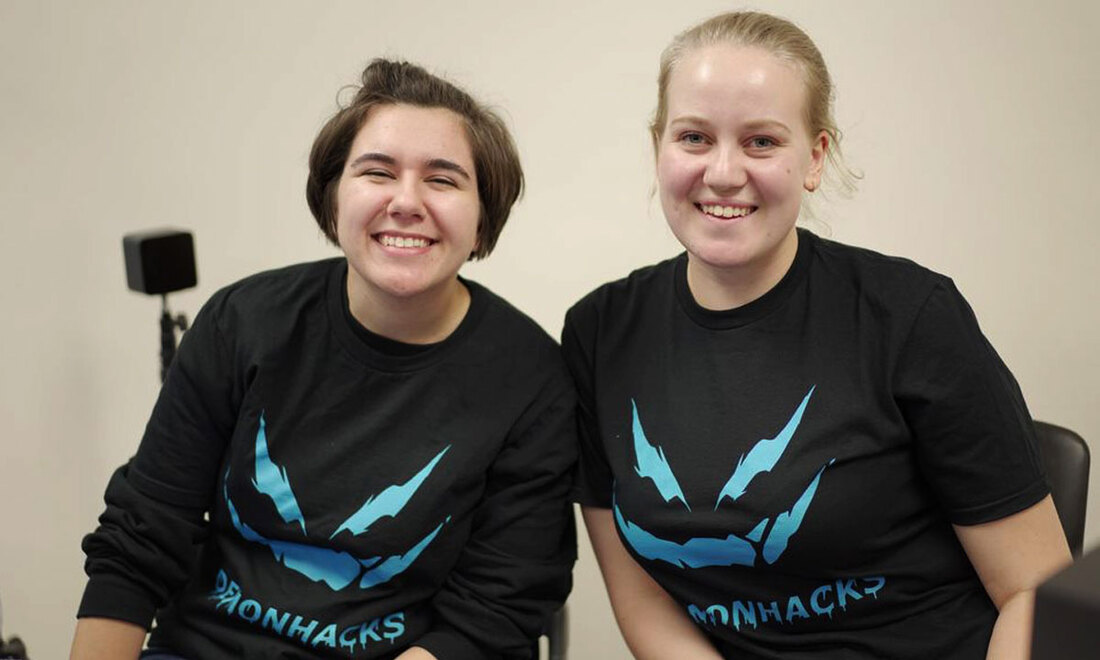 two women students wearing DemonHacks shirts and smiling