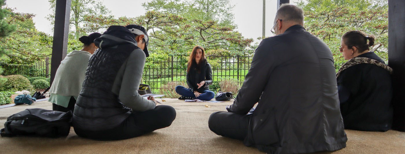 a group of people sit on the ground in a circle taking notes and talking together