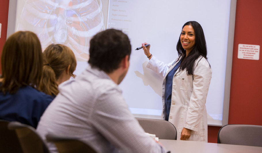 Graduate assistant discussing material in front of a white board to the class.