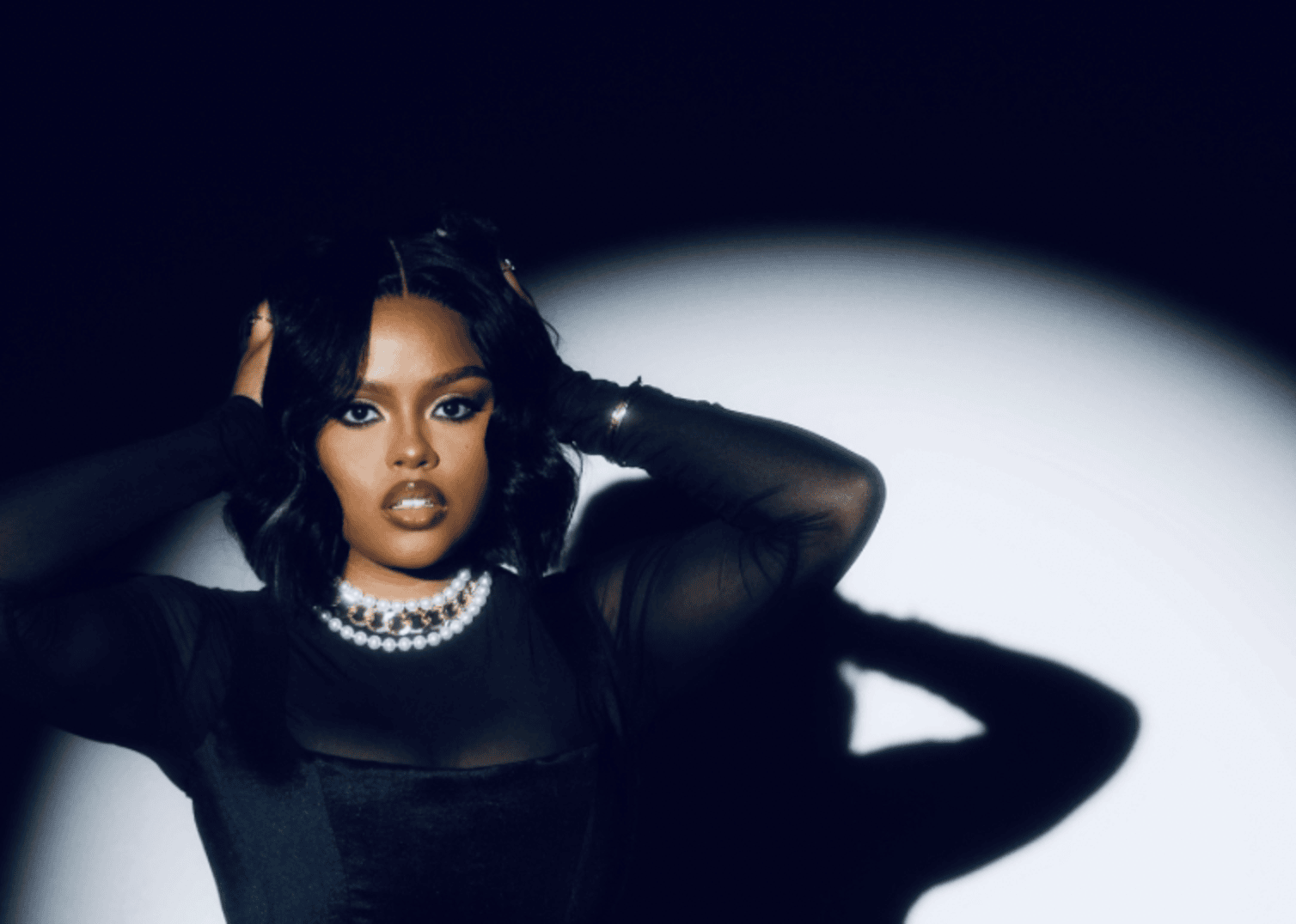 Deja Blackwell posing with her hands on her head. She wears an all black outfit.