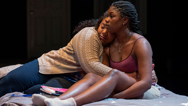 Actors on stage presenting a scene of physical intimacy.