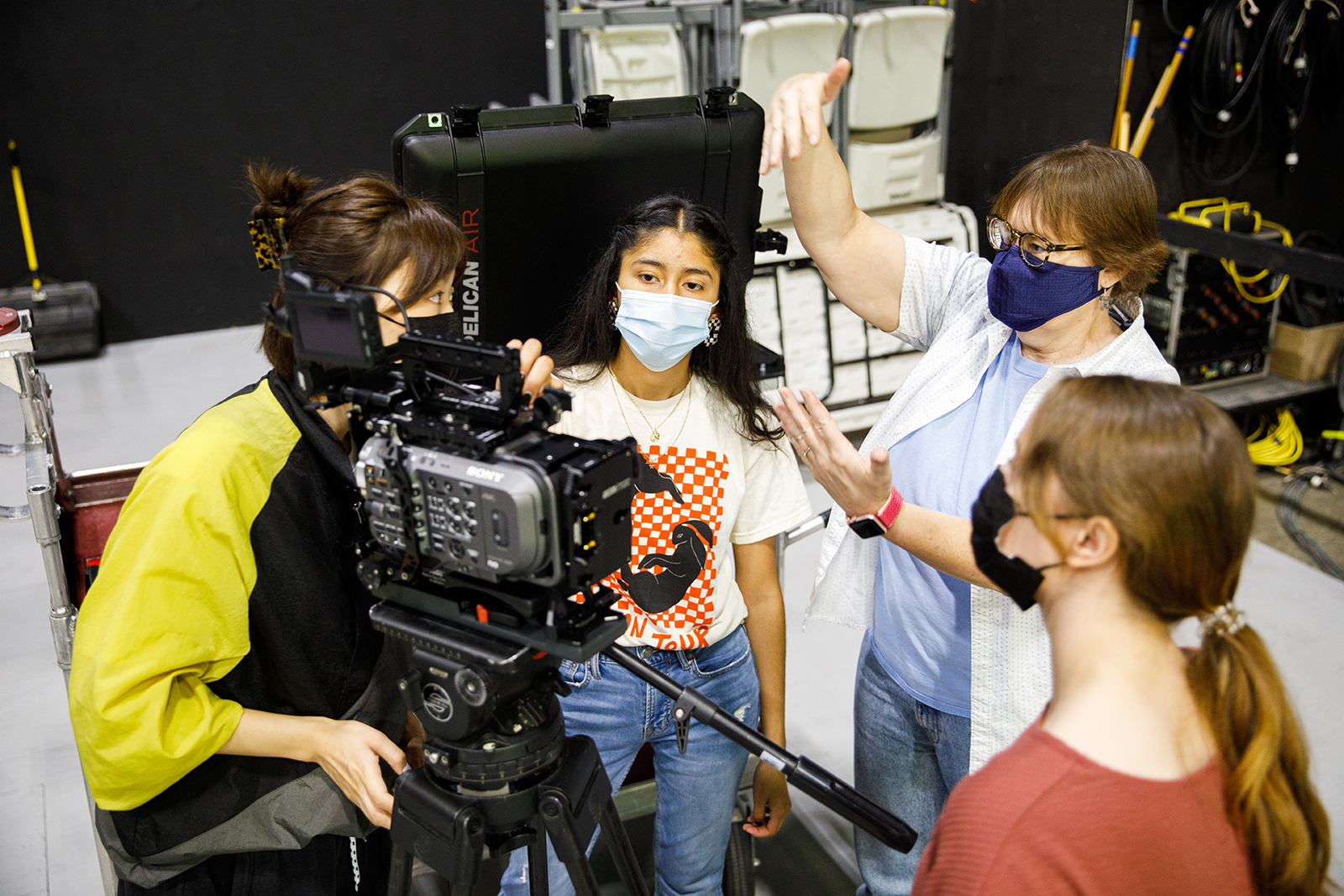 Three students with a camera listen to Dana Kupper