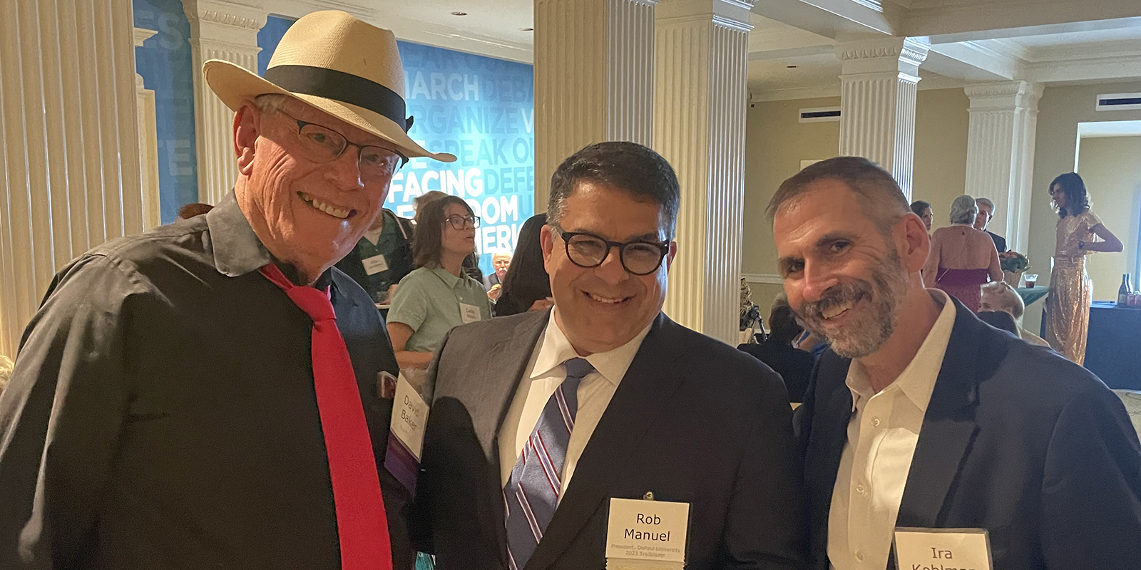 President Rob Manuel stands with two representatives of The Village Chicago at an event