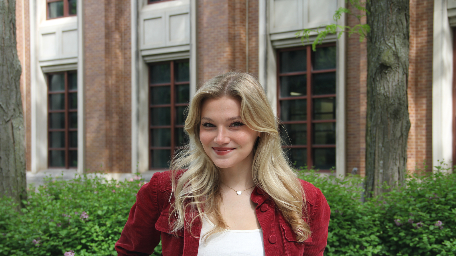 A photo of Lily Kate Cobb on DePaul's Lincoln Park Campus wearing a white shirt and a red jacket