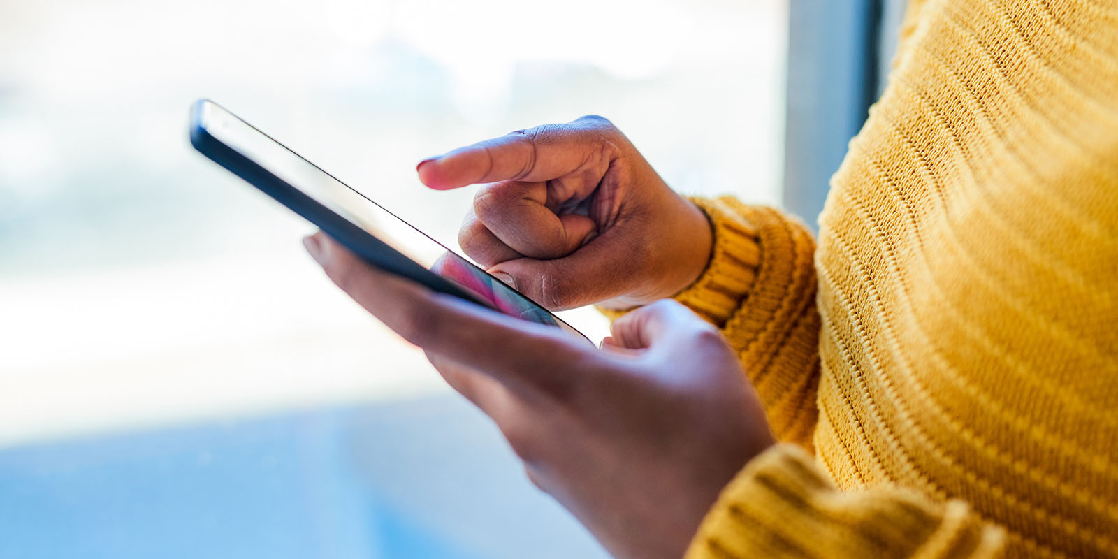 Silhouette of a person holding a phone and scrolling with a finger