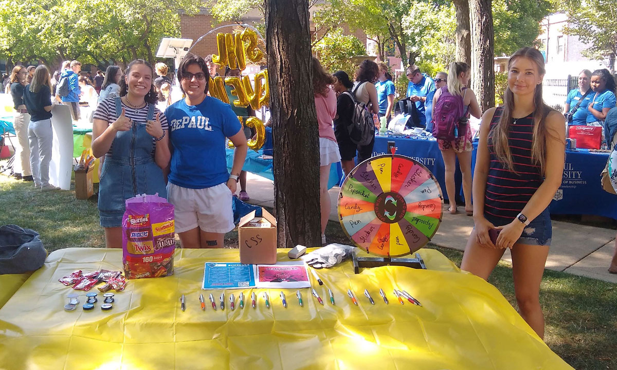 students ouside at a booth welcoming guests