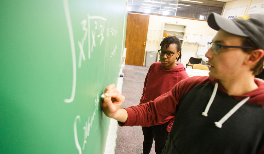 Two students writing an a chalkboard.