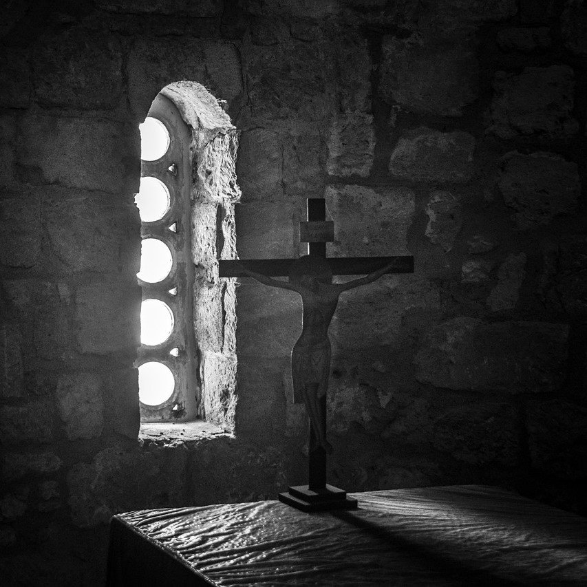 Light streaming onto a crucifix in dark room