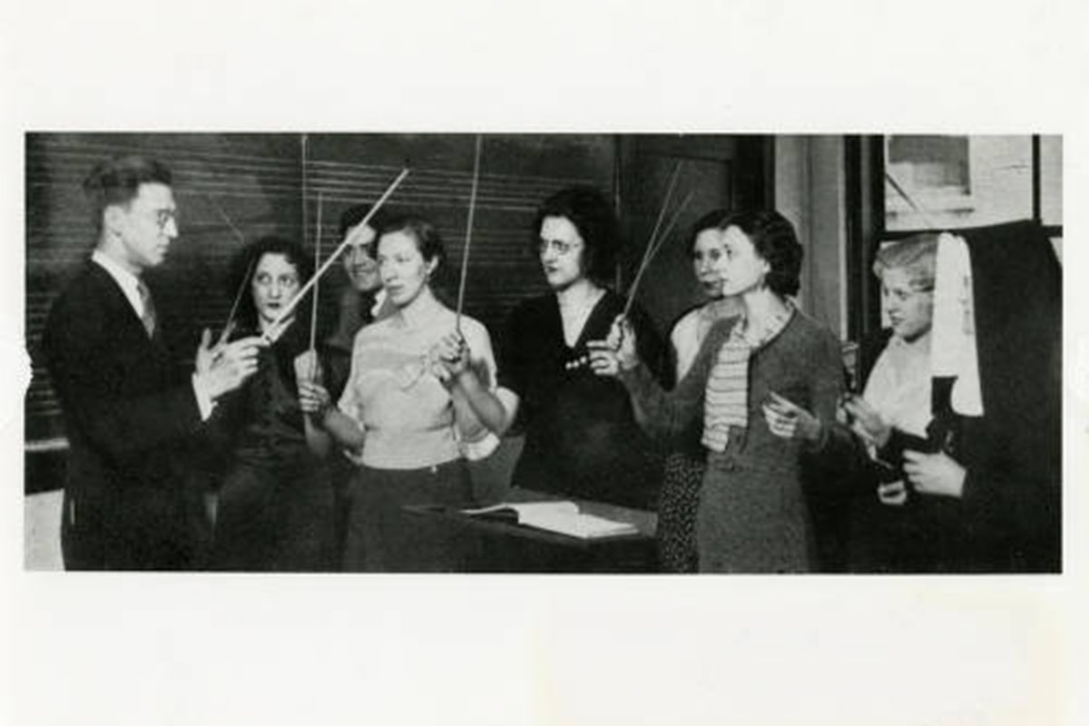 Man shows a group of women how to hold a baton