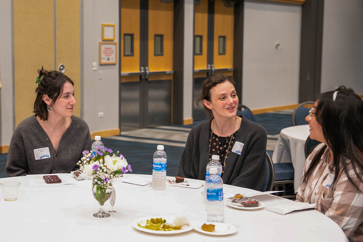 Four people sit around a table talking.