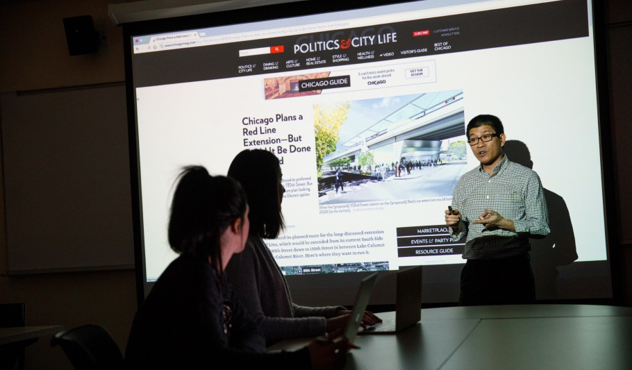 Faculty and students speaking in a dark room using projector screen