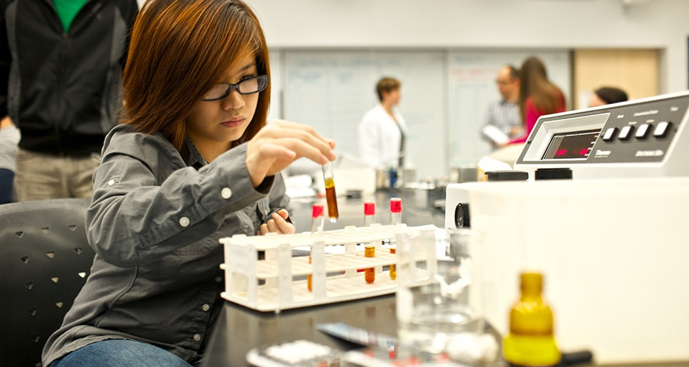 A student observing test tubes in a lab.