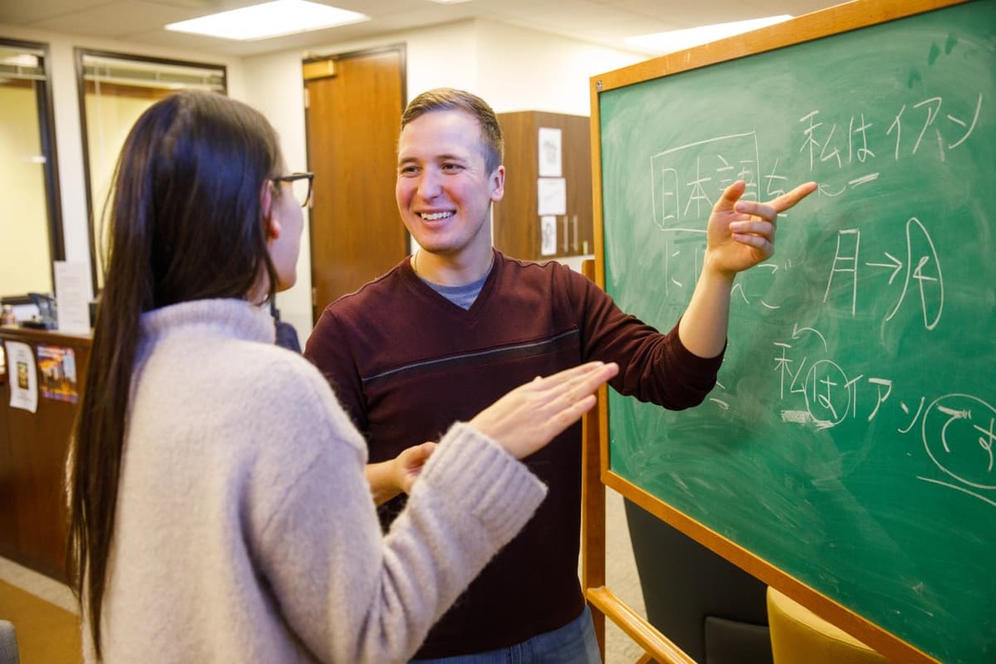 two students discussing at chalkboard