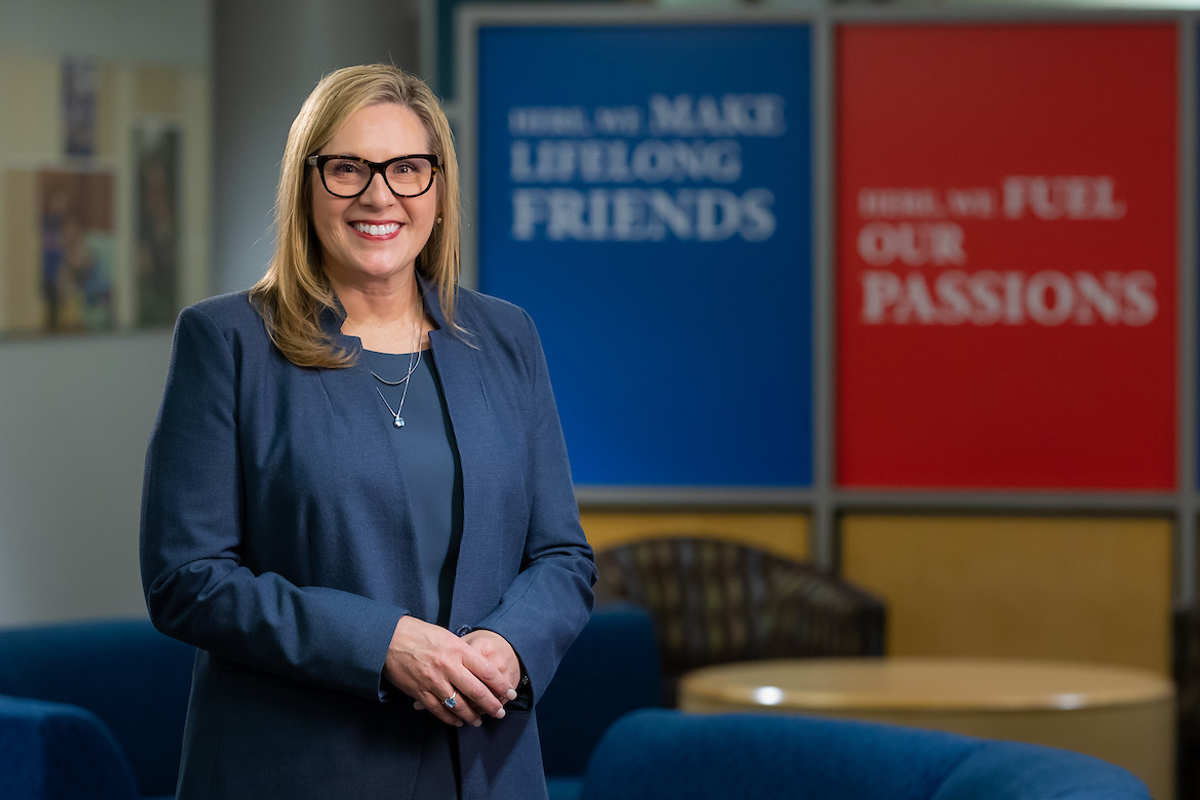 Woman in blue suit poses in empty conference room