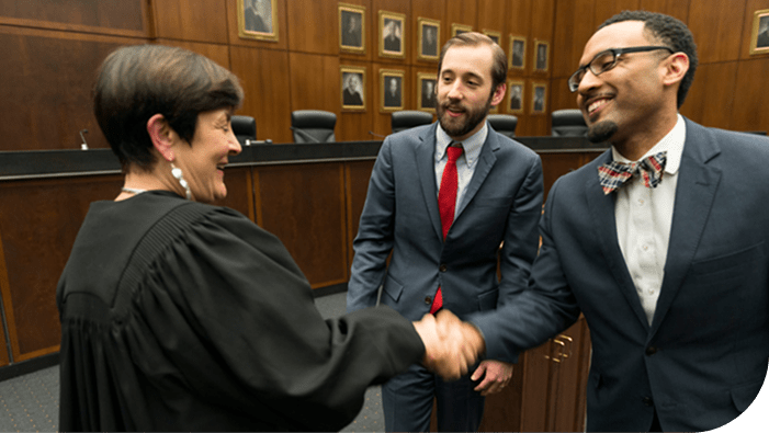 Two male DePaul Law students speaking with a female judge