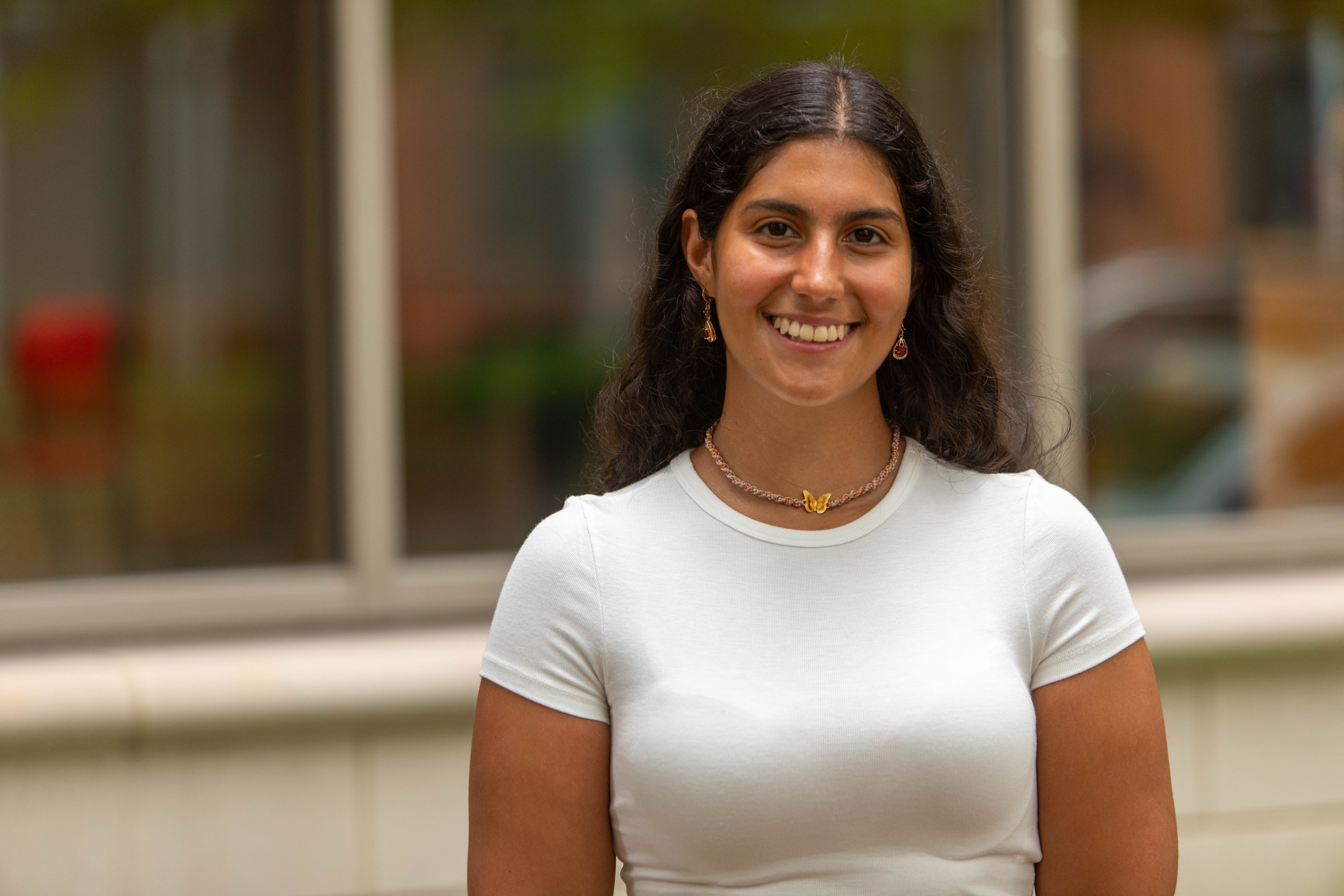 An image of Juliana Zanubi wearing a white shirt on a blurred background.