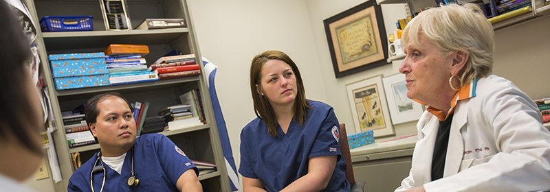Two students listening to their professor in her office.
