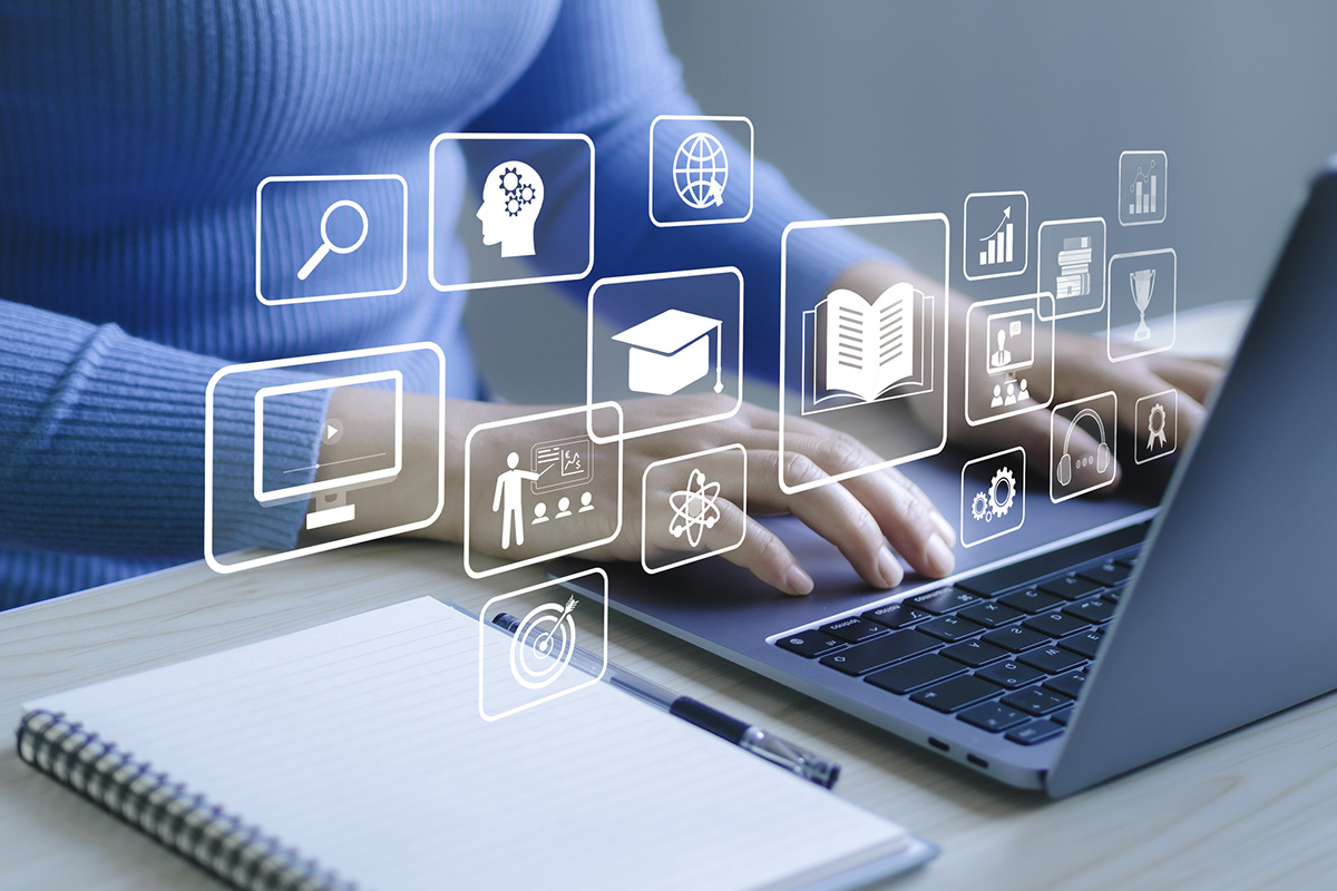 Hands typing on laptop with e-learning icons