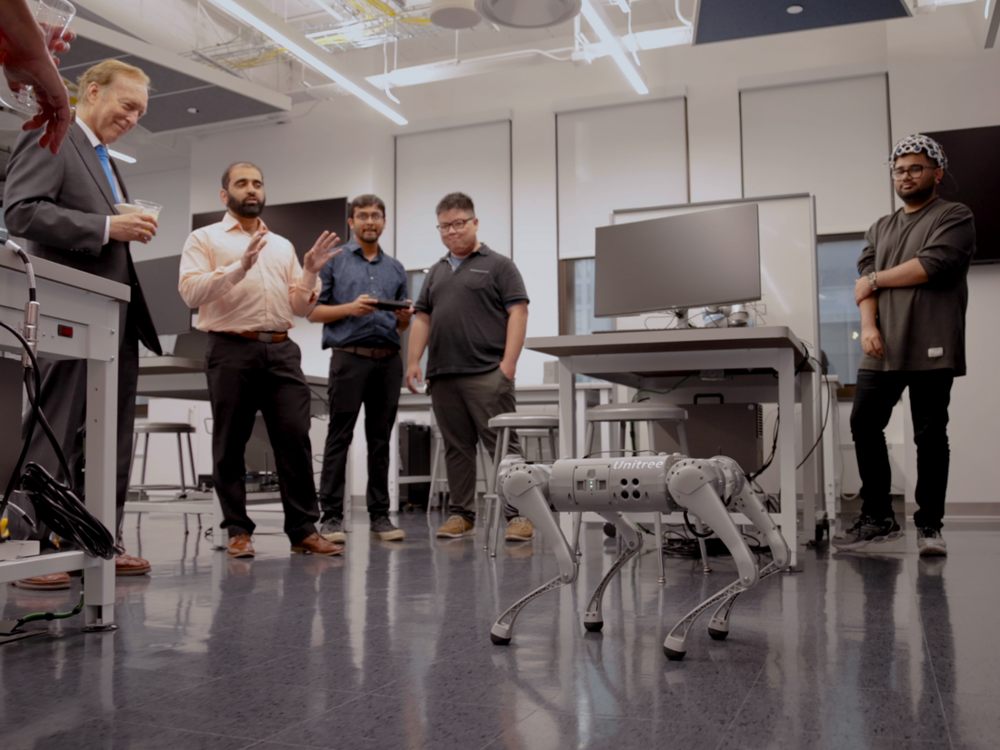 faculty and students look at quadruped robot in lab