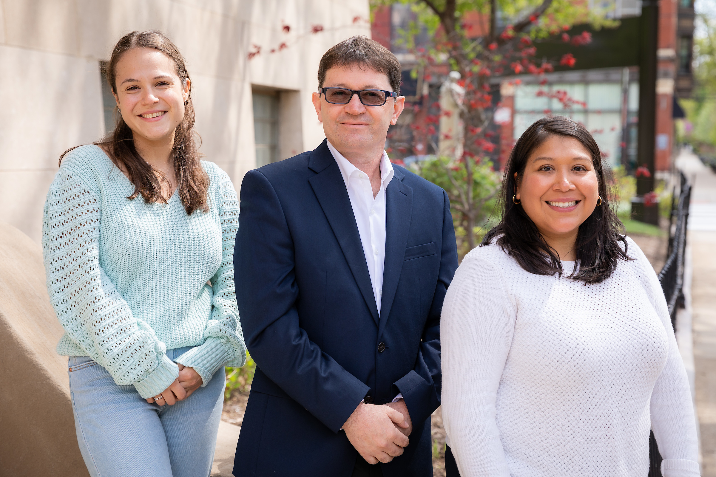 A woman with brown hair and a light blue sweater, a man wearing glasses and a suit, and a woman wearing a white sweater