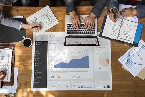 a desk with coffee cups, laptops, and business chart graphics