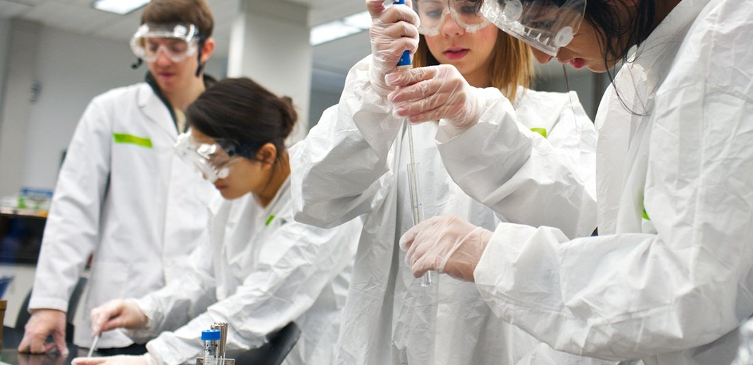 Four students conducting an experiment in lab gear.